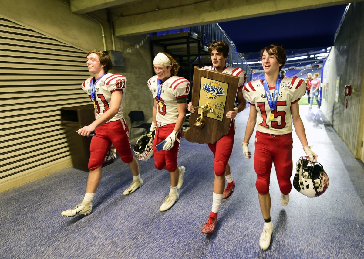 New Palestine's left to right, Kade Large, Brody Luker, Eric Roudebush and Ryker Large walk off the field moments after winning the IHSAA 5A State Championship Trophy after defeating Valparaiso, 27-21, in the state final on Friday, Nov. 29, 2019. (Tom Russo | Daily Reporter)