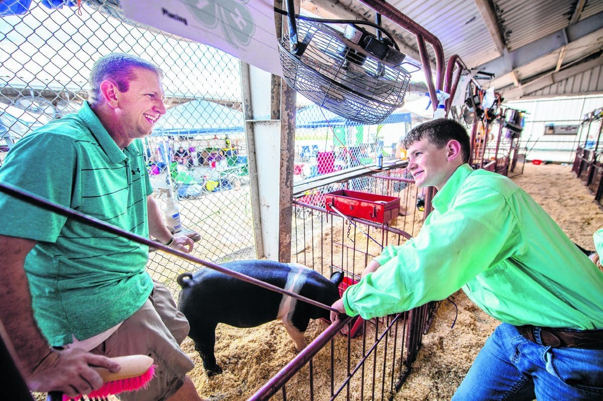 Eric Schilling, left, and son Luke, 14, work together preparing for the 4-H Swine Show at the Hancock County Fair on Sunday, June 20. (Tom Russo | Daily Reporter)