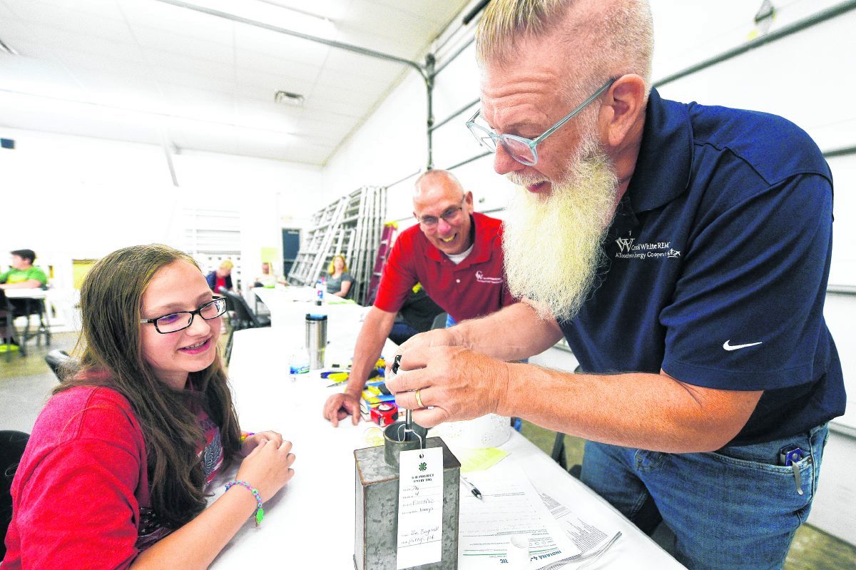 Zoe Bagnall, far left, listens as judges Joel Roper and Joe Spear look over her lamp entry in the Electricity category. (Tom Russo | Daily Reporter)